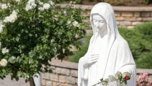 Pellegrino in preghiera a Medjugorje davanti alla statua della Regina della Pace